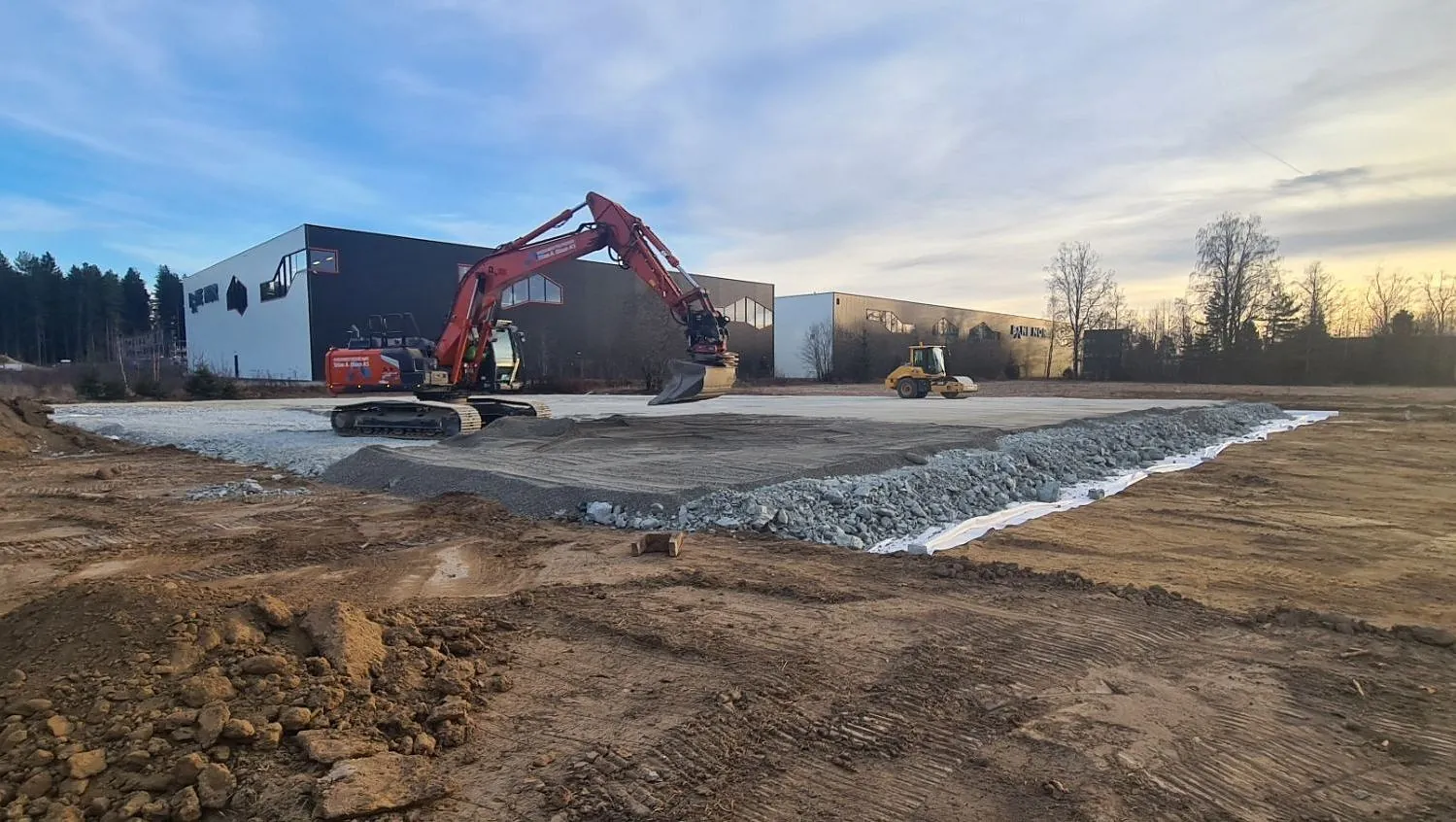 Nedgravde kabler markert med rødt bånd i grøft, gravemaskin og lastebil bak.