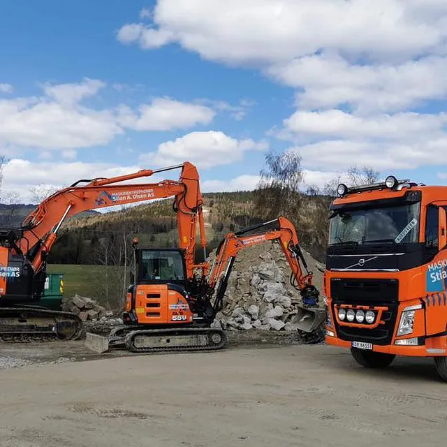 Gravemaskiner og lastebil jobber med steinmasser på anleggsområde